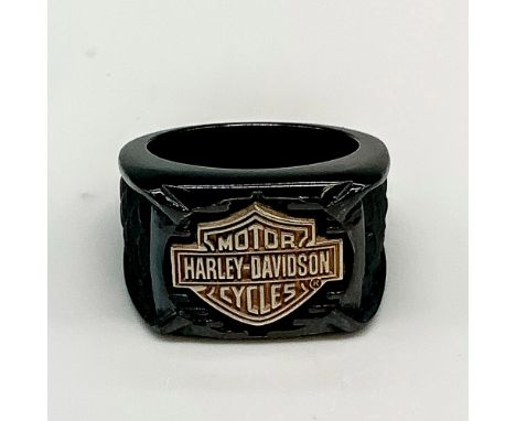 Black band with a large copper tone Harley Davidson logo in the front and textured dark grey scales carved on either side. Ti