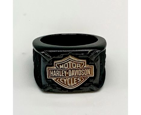 Black band with a large copper tone Harley Davidson logo in the front and textured dark grey scales carved on either side. Ti