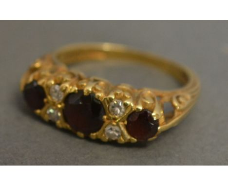 An 18ct Gold Diamond and Garnet Set Ring with three garnets interspaced with four diamonds