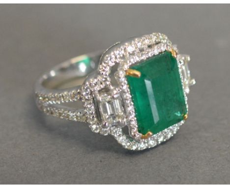 An 18ct. White Gold Art Deco Style Emerald and Diamond Ring, with a rectangular emerald flanked by baguette diamonds and smal