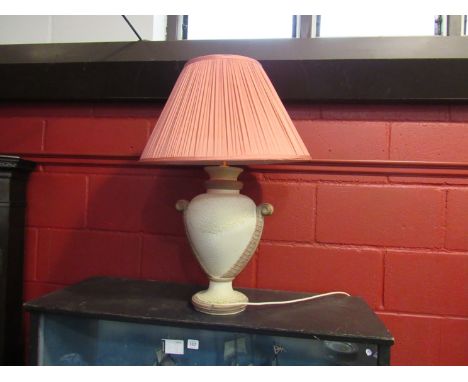 A large urn shaped pottery lamp base with pink pleated shade  