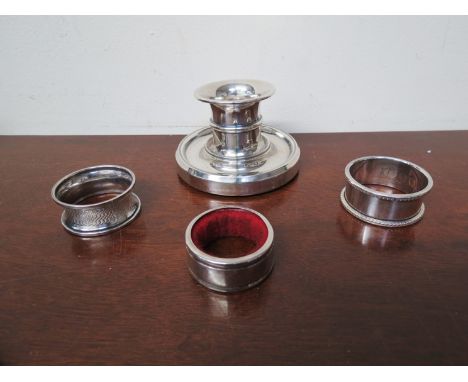 A silver squat form candlestick, two napkin rings and bottle topper