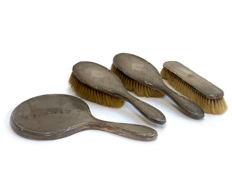 An engine turned silver dressing table set, comprising clothes brush, two hairbrushes, and looking glass, hallmarked Chester 