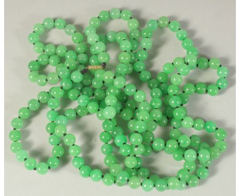 A VERY LONG STRING OF JADE BEADS with gold clasp. 60ins long.