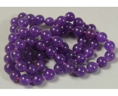 A STRING OF EIGHTY BLUE JADE BEADS 26ins long.