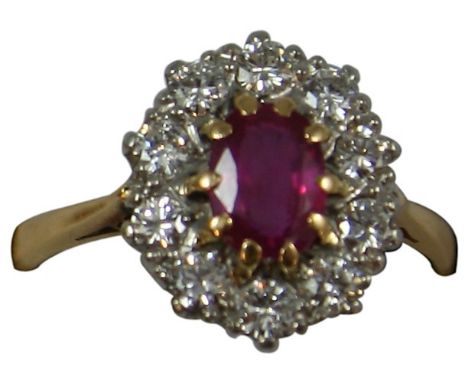 An 18ct gold ruby and diamond cluster ring, claw set with an oval mixed cut stone bordered by ten brilliants, diamond weight 