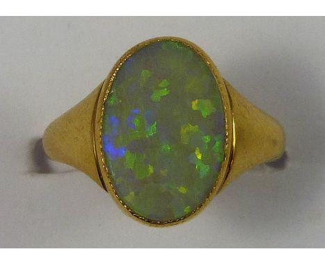 An 18ct gold opal dress ring, collet set with an oval stone, size G.