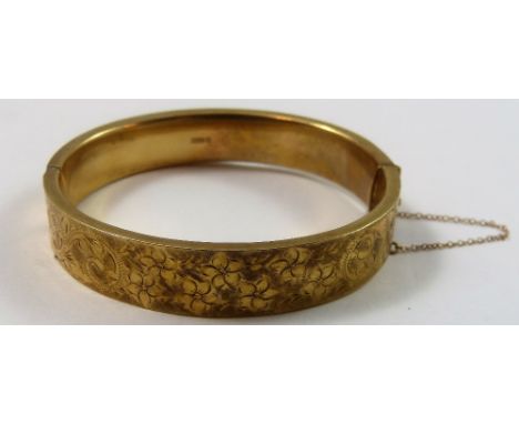 A 9ct gold hinged bangle, Birmingham 1968, the front panel with floral engraved decoration, weight 18 grams.