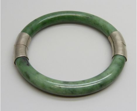 An Oriental nephrite bangle with white metal mounts, 43g, 6cm