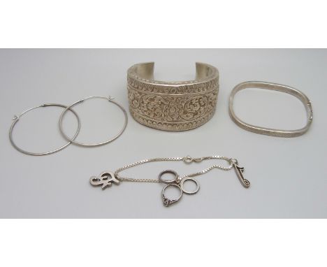 An Eastern white metal bangle, 4cm wide, a silver bracelet with charms and a pair of silver hoop earrings, 61g