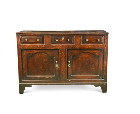 An oak dresser base, 18th century, the rectangular top over three short drawers above two cupboard doors raised on bracket fe
