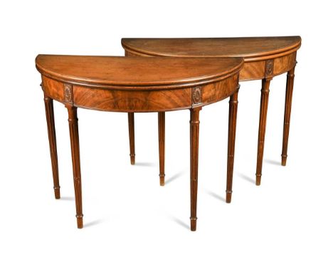 A pair of George III mahogany demi-lune card tables, the moulded fold over tops with baize lining, raised on patera-headed tu