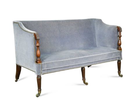 A mahogany framed settee, early 19th century, the shaped arms with turned column supports raised on three tapered and fluted 