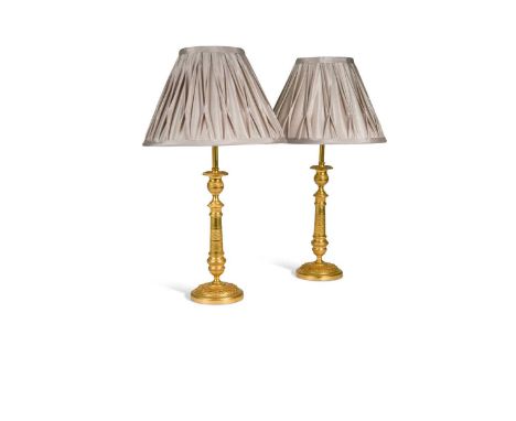 A pair of Regency engine turned ormolu candlestick lamps, circa 1820, with modern conversion to electricity39.5cm to top of l