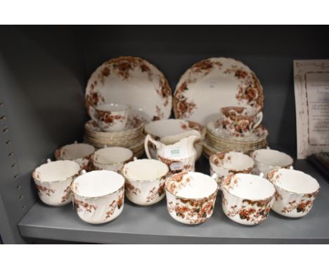 An antique partial tea service including cups and saucers,plates of varying size, jug and sugar basin, having brown and navy 