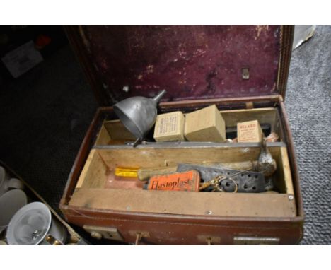 A vintage suitcase containing a selection of tools, tins, funnel and more.
