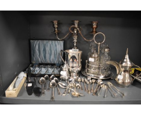 An assortment of plated ware and cutlery including candle stick holder,boxed tea spoons, condiment set and more.