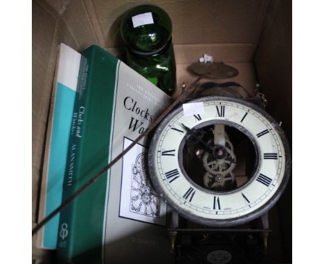 A reproduction lantern clock, two books on horology and a green glass jar of coins