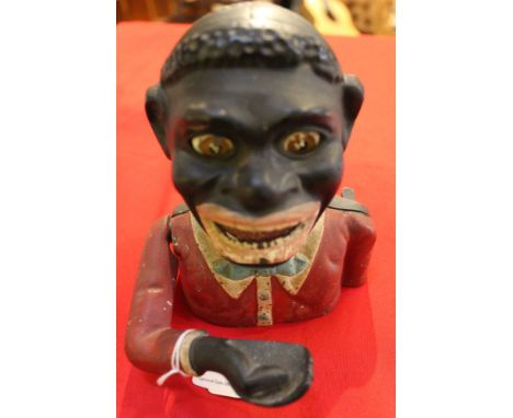 A cast iron money box with articulated arm These items are listed on the basis they are illustrative of a bygone culture in w