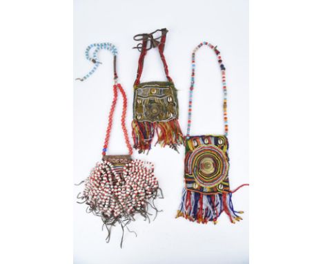 Three Ethiopian beaded necklaces coloured glass beads, cowrie shells and leather, two with an applied brass disc, one with a 
