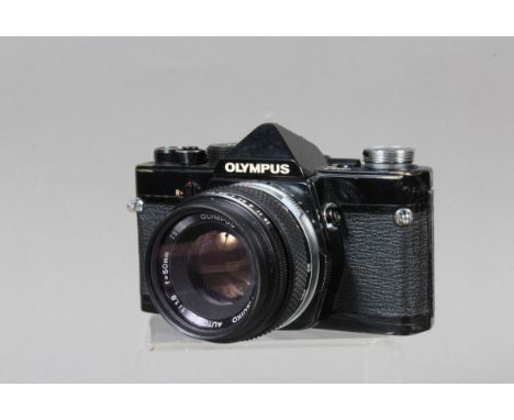 An Olympus OM-1 SLR Camera, black, serial no 888691, shutter working, meter responsive, self timer working,  body G, brassing