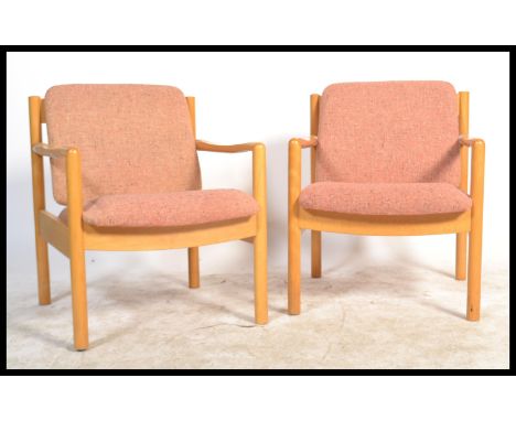 A pair of 20th century Ercol staff chairs. Light beech wood turned construction with shaped elbow rests having upholstered se