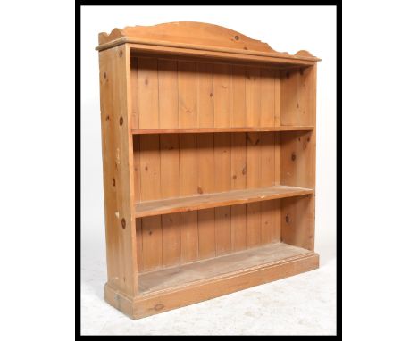 An antique style large open window country pine bookcase cabinet having a plinth base with a series of fixed shelves. The top