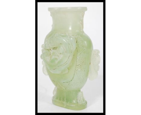 A Chinese jade vase raised on a pedestal base depicting dragons with twin dragon handles.