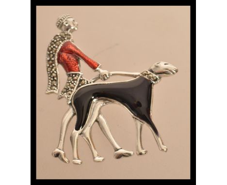 A sterling silver and enamel art deco brooch in the form of a lady walking her dog. Weighs 11 grams.