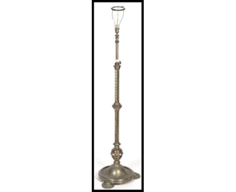 A polished metal rococo revival standard lamp being raised on a terraced base with pad feet and a spiral twist column with el