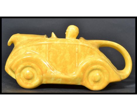 A Sadler art Deco ceramic novelty teapot modelled as a racing car and driver in mottled yellow colourway, black Sadler stamp 