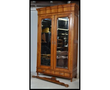 An early 20th century French armoire double wardrobe having stunning twin mirror doors raised on a shaped plinth base and cul