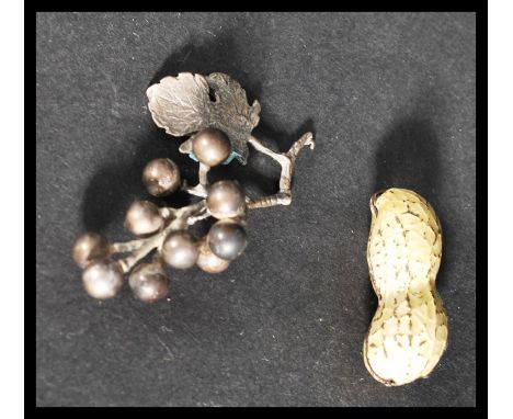 An unusual enamel pill pot box in the form of a peanut along with a silver white metal grapes and vine miniature.