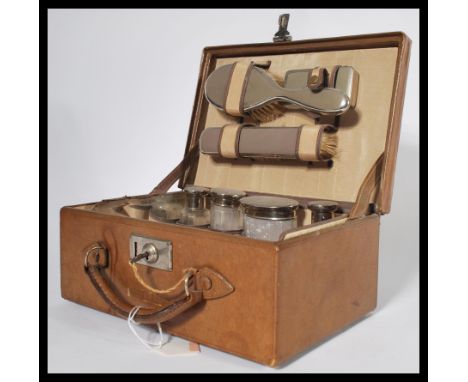 A vintage early 20th century gents vanity case fully appointed with silver white metal topped bottles and phials with brushes