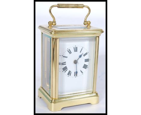 An early 20th century gilt brass French carriage clock having a white enamel face with Roman numeral chapter ring and faceted
