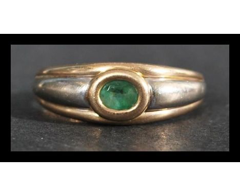 A hallmarked 9ct white and yellow gold ring with an oval cut bezel set emerald. Import mark for Birmingham. Weight 3g. Size R