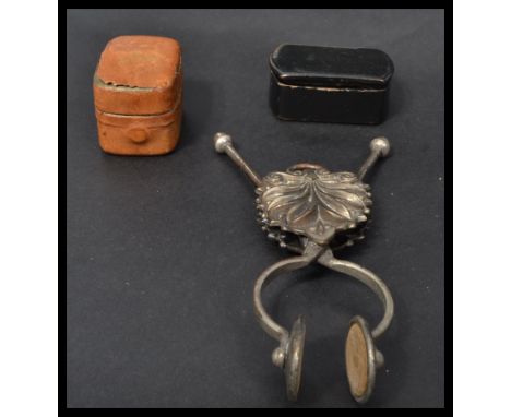 A 19th century brass skirt lifter, the scissor action with two circular clamps and a stylised leaf boss with suspension loop 
