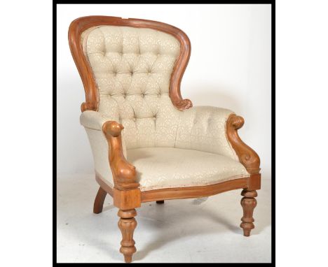 A Victorian style mahogany spoon back armchair raised on reeded turned legs with button backed fabric and show wood spoon bac