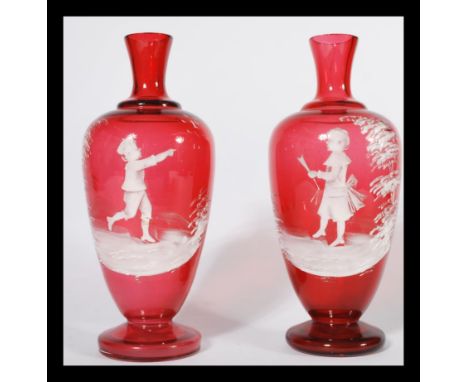 A pair of Mary Gregory style cranberry glass vases, late 19th century, with white opaque enamel decoration, young child in wo