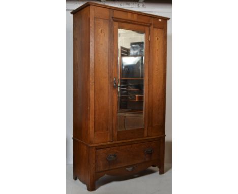 An&nbsp; Edwardian Arts &amp; Crafts light oak wardrobe&nbsp; having a plinth drawer base with central mirror door flanked by