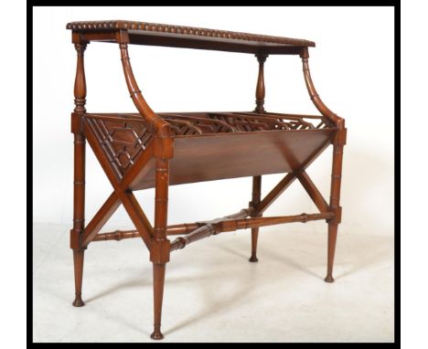 A Regency style carved mahogany two tier book trough with open fretwork and raised on turned tapering supports.