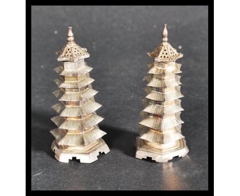 A pair of early 20th century Chinese silver pepperettes in the form of pagoda buildings. The seven tier buildings having pier
