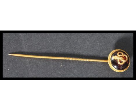 A yellow metal tests as 18ct gold stick pin brooch having an applied snake motif on red stone back. Weighs 4.1 grams