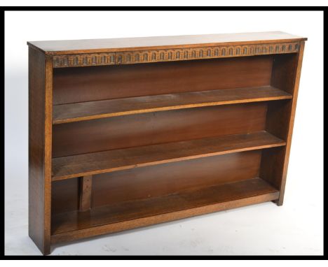 An antique style oak open window bookcase cabinet raised on a plinth base with central shelf and flared top. Of low and wide 