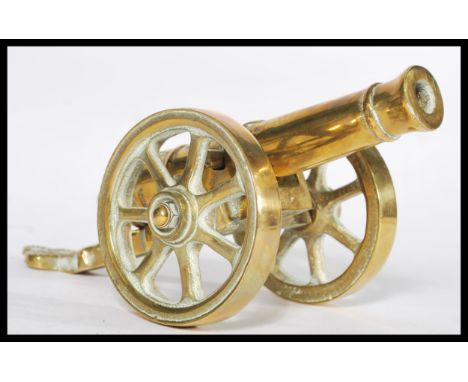 An early 20th century heavy cast brass desk top cannon dated 1812, Moving wheels with detachable cannon. Measures 13 cm high,