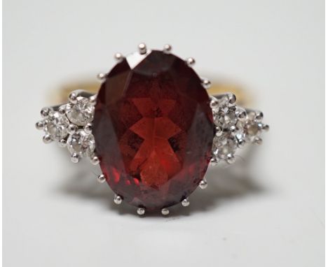 A modern 18ct gold and oval cut garnet set dress ring, with six stone diamond set shoulders, size M/N, gross weight 4.8 grams