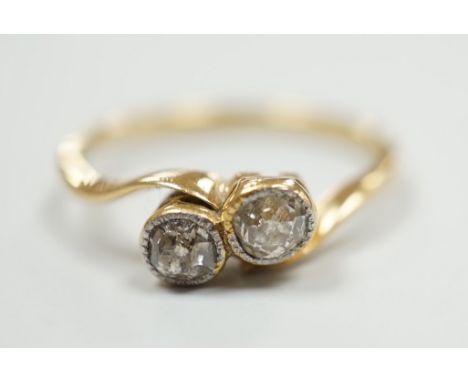 A yellow metal and collet set two stone diamond cross over ring, size L, gross weight 1.9 grams.