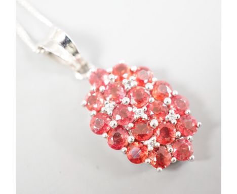 A modern 375 white metal, sunset ruby and white sapphire set cluster pendant, 19mm, on a 375 white metal chain, 42cm, gross 4
