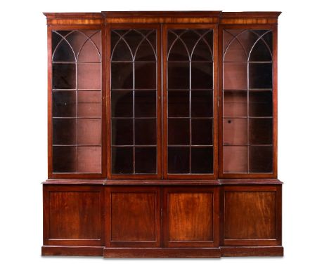 A George III mahogany breakfront library bookcase, with gothic arched glazed doors above and panelled doors below, adjustable