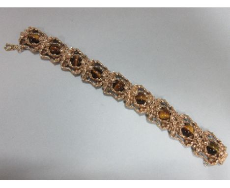 A 9ct gold and tiger's eye bracelet, the nine pierced, deeply-modelled, heavy cast links each set with a round cabochon tiger